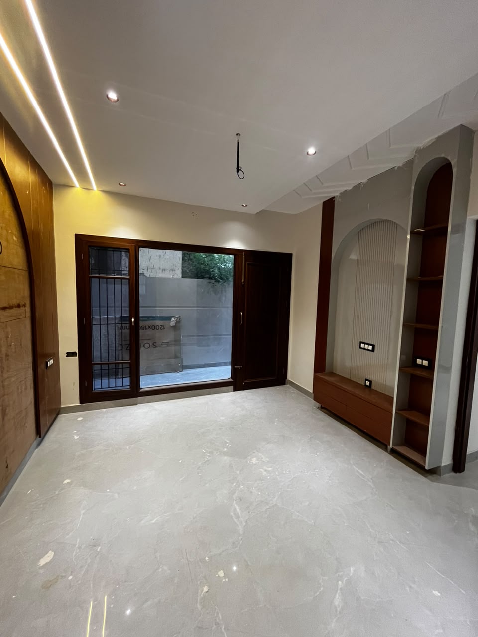 Living room with marble floor, warm cove lighting and arched wooden niches