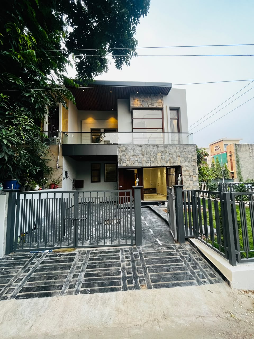 Modern stone-clad villa entrance behind a dark metal gate