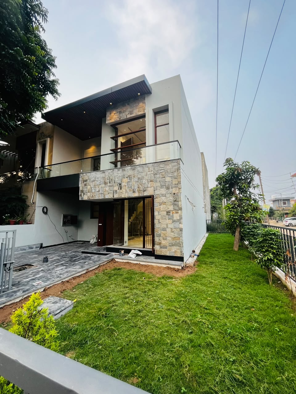 Contemporary two-storey villa with stone cladding, glass balcony and a private lawn